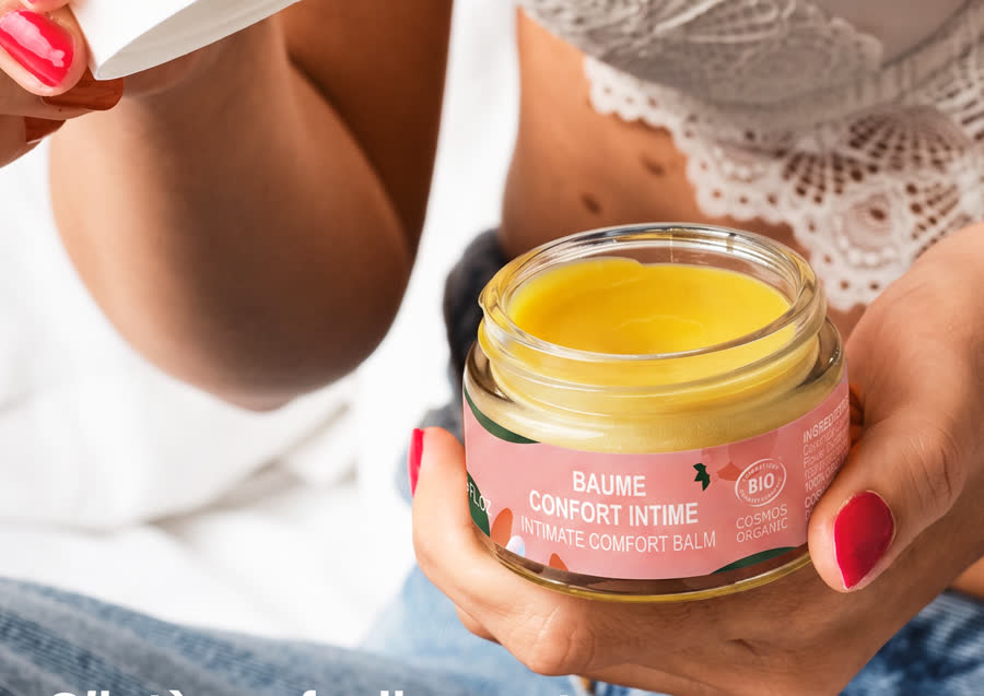 Une femme ouvre un pot de baume confort intime Goliate