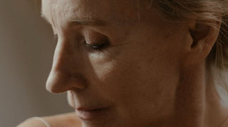Visage d'une femme aux cheveux gris, yeux fermés, dans une lumière douce