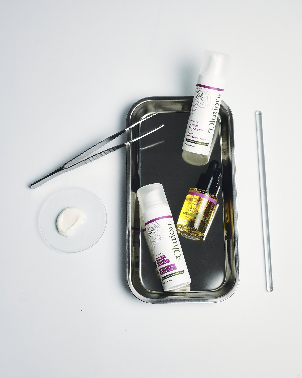 Soins Active-Lift oOlution sur un plateau de laboratoire en inox, pince et coupelle de crème