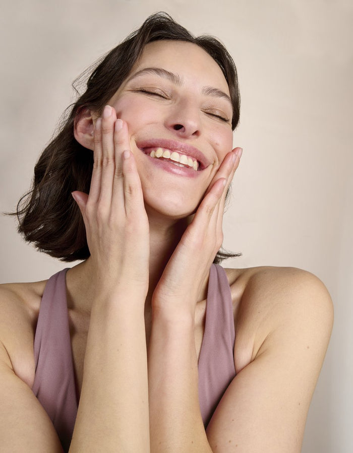 Femme souriante, les mains sur le visage