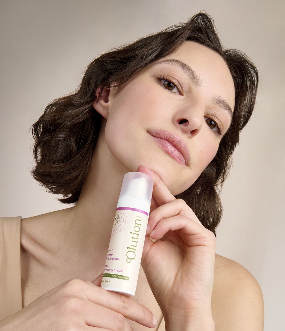 Femme tenant La crème anti-âge global contre son cou